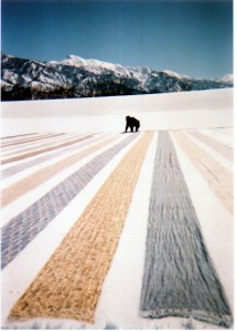 冷たい雪とあたたかい太陽の不思議な力が布地を成長させる。遠く魚沼の山並みと越後三山が美しい。